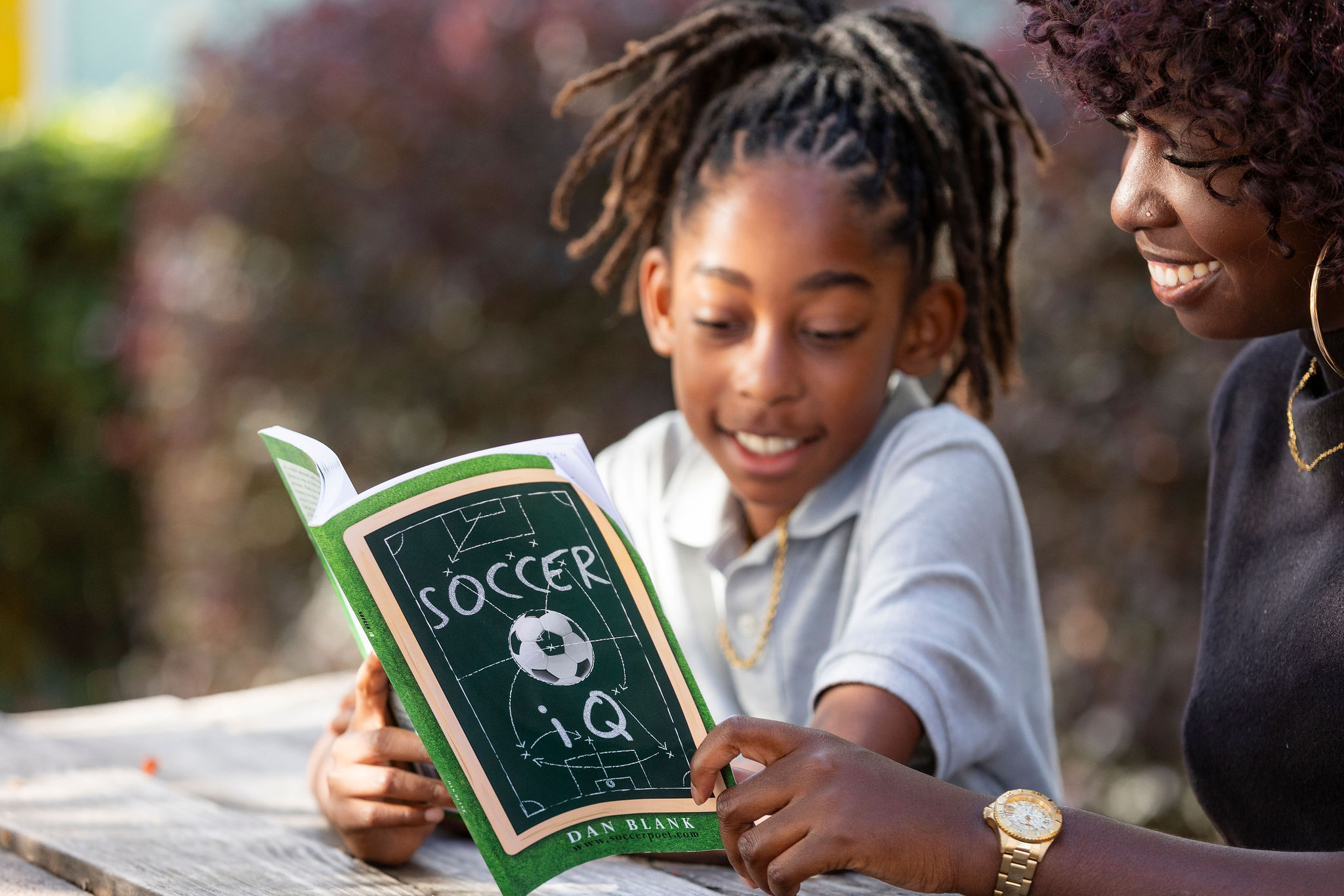 Daughter and mother reading book outside