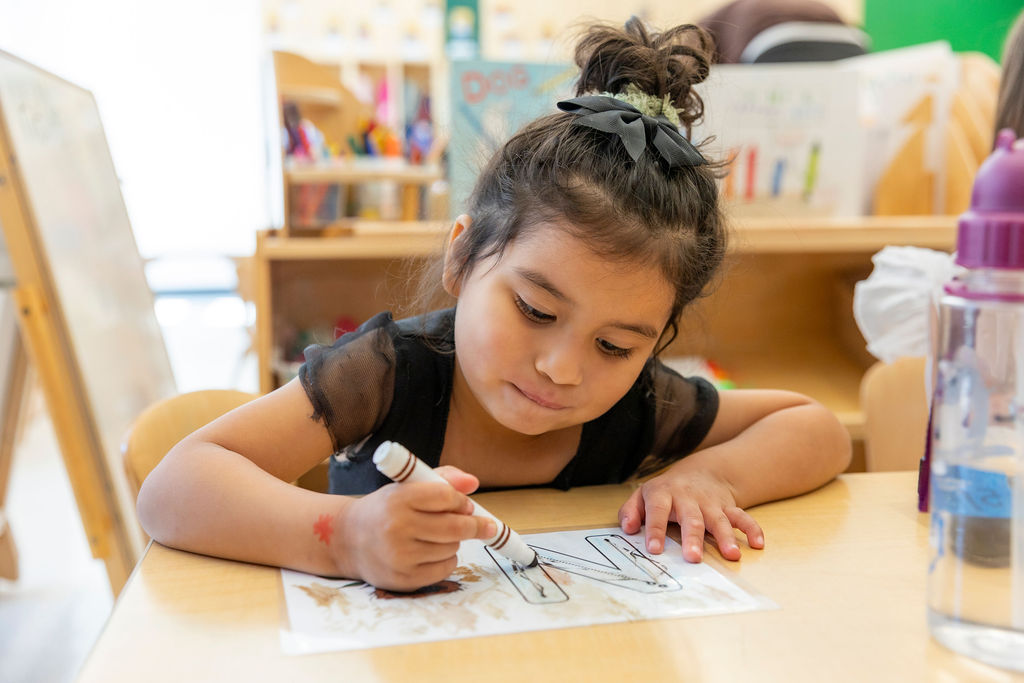 Young child using marker on a worksheet at E3 School
