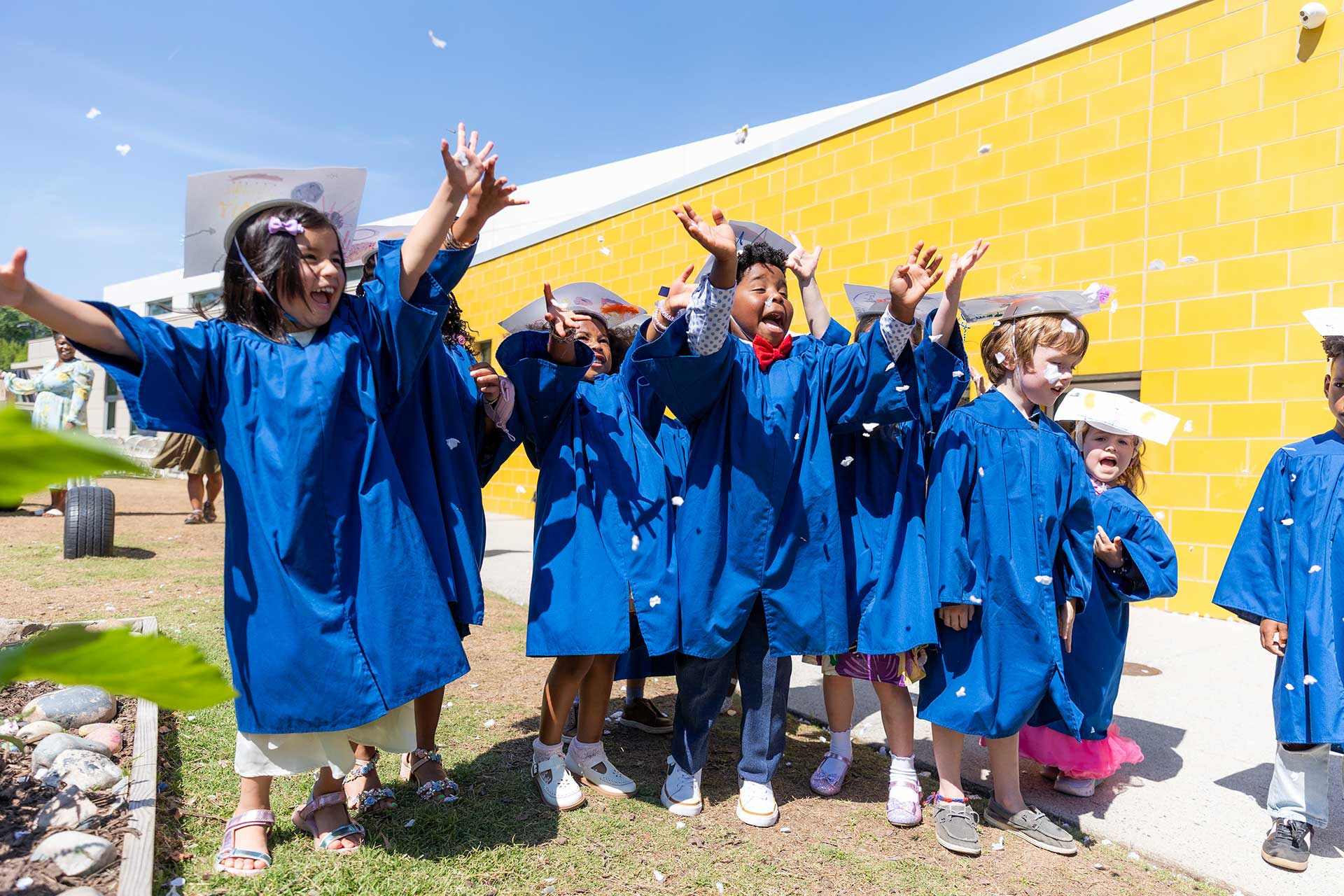 E3 School children wearing graduation gowns, smiling and celebrating their achievements together.